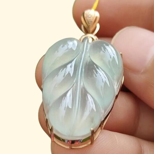 une main tenant un pendentif en jade