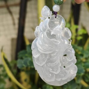 a hand holding a jade pendant