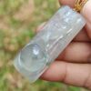 a hand holding a jade pendant