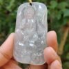 a hand holding a jade pendant