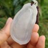 a hand holding a white pendant