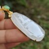 a hand holding a jade pendant