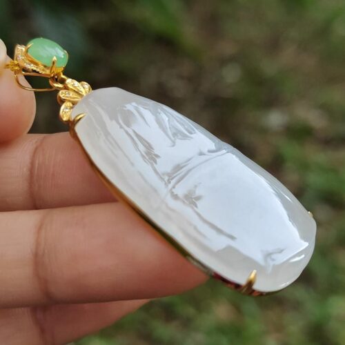 a hand holding a jade pendant