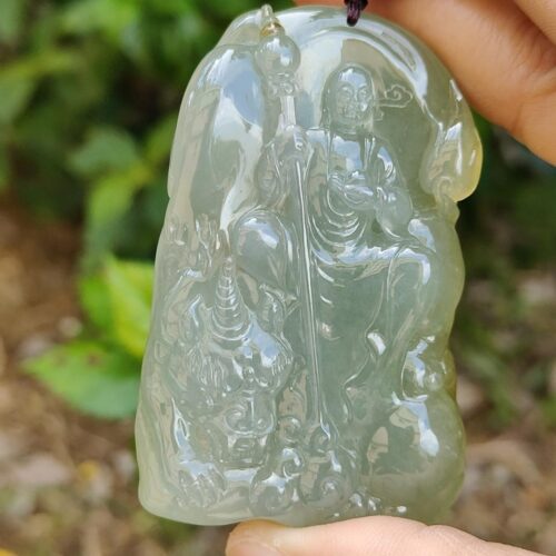 a hand holding a jade pendant