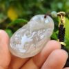 a hand holding a jade pendant