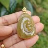 a hand holding a jade pendant
