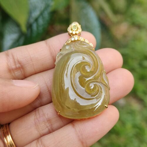 a hand holding a jade pendant