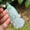 a hand holding a jade pendant