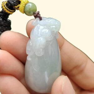 a hand holding a jade pendant