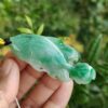 a hand holding a jade fish pendant