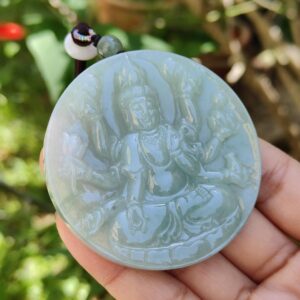 Una mano sosteniendo un medallón de jade.