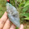 Una mano sosteniendo un colgante de jade.