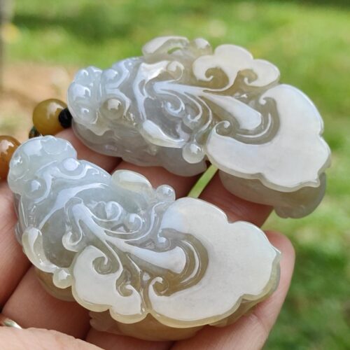 a hand holding a pair of jade carved pieces