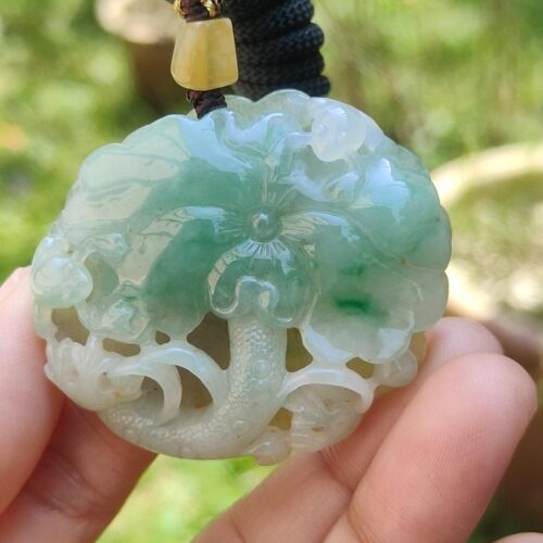 a hand holding a jade pendant