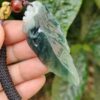 a hand holding a jade leaf pendant