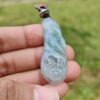 a hand holding a jade pendant
