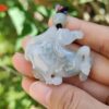 a hand holding a jade horse pendant