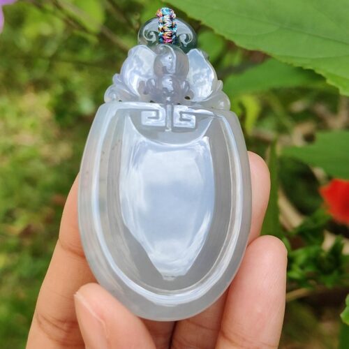 một bàn tay cầm một mặt dây chuyền ngọc bích