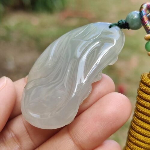 a hand holding a jade pendant