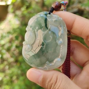 a hand holding a jade pendant