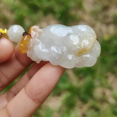 a hand holding a white and yellow bead