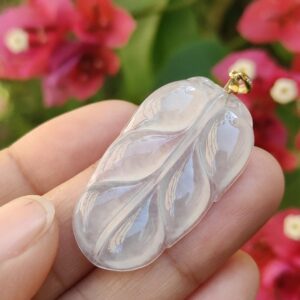 một bàn tay cầm một mặt dây chuyền hình chiếc lá trong suốt