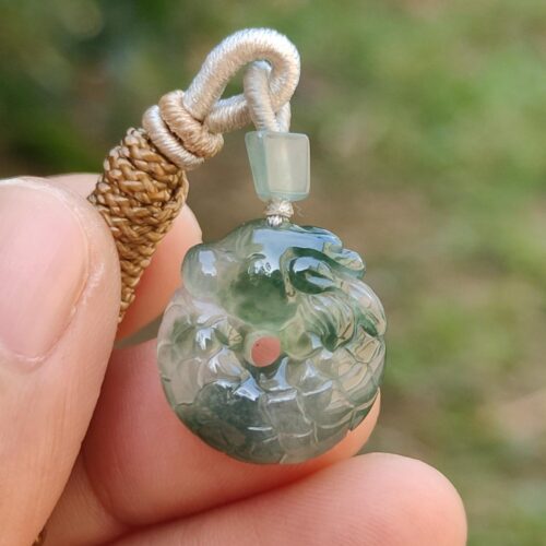 a hand holding a jade pendant