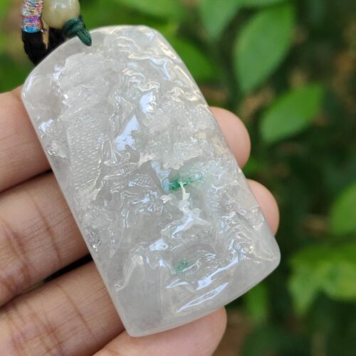 a hand holding a white and green necklace