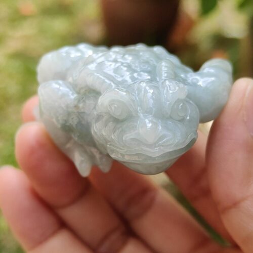 a hand holding a jade frog