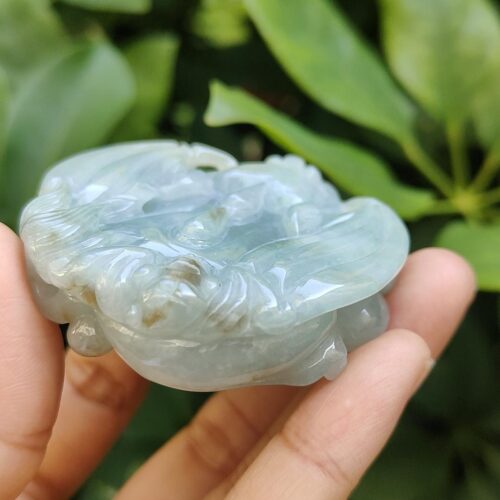 une main tenant un objet en jade