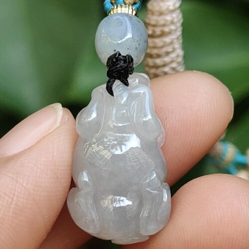 a hand holding a jade pendant