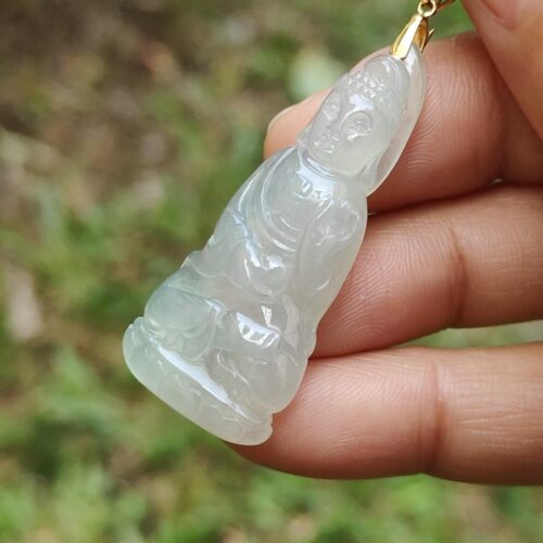a hand holding a jade pendant