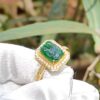 a ring with a green stone in a gold ring with diamonds