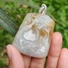 Una mano sosteniendo un colgante de jade.