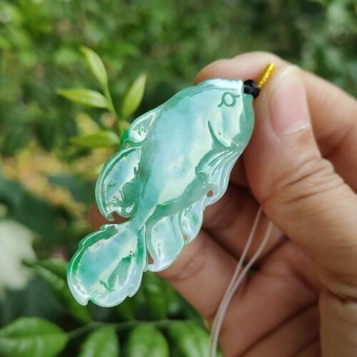 a hand holding a green fish pendant
