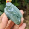 a hand holding a jade pendant