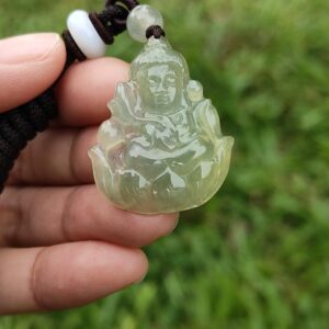 a hand holding a jade pendant