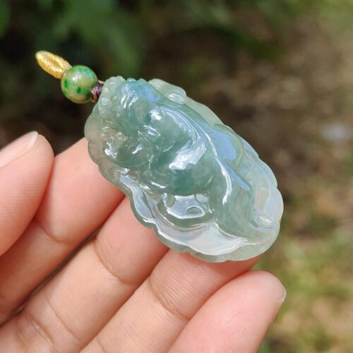 a hand holding a jade pendant