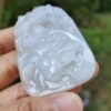 a hand holding a white jade object