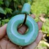 a hand holding a jade pendant