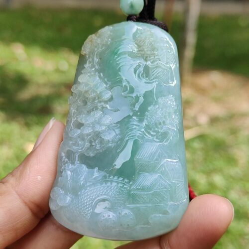 a hand holding a jade pendant