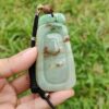 a hand holding a jade pendant