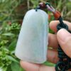 une main tenant un pendentif en jade