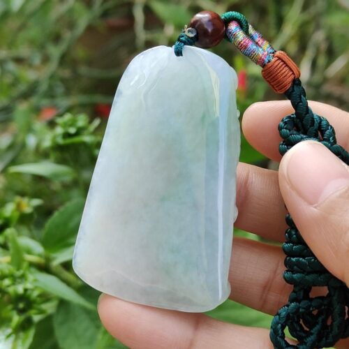 une main tenant un pendentif en jade