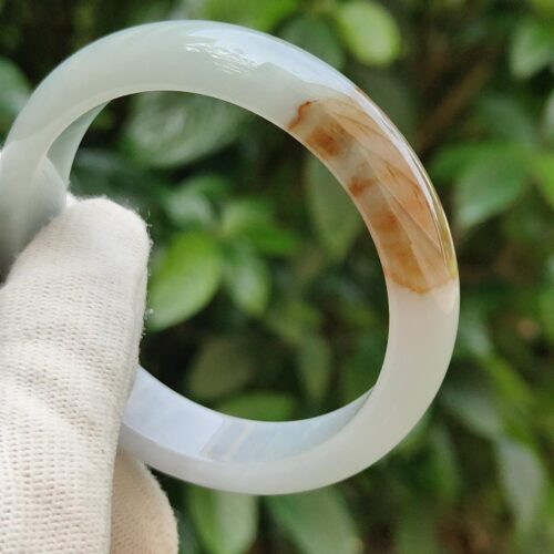a hand holding a white and brown ring