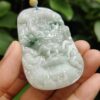 a hand holding a jade pendant