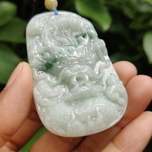 a hand holding a jade pendant
