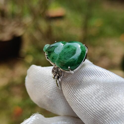 a hand wearing a gloved finger ring with a green bug