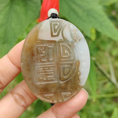 Una mano sosteniendo un colgante de piedra.