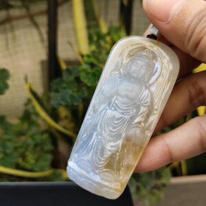 a hand holding a jade pendant